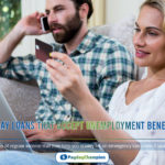 Woman holding debit card by man talking on phone with laptop