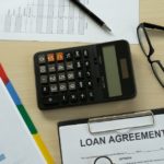 A calculator and loan agreement on a desk with a Title Loans sign above it