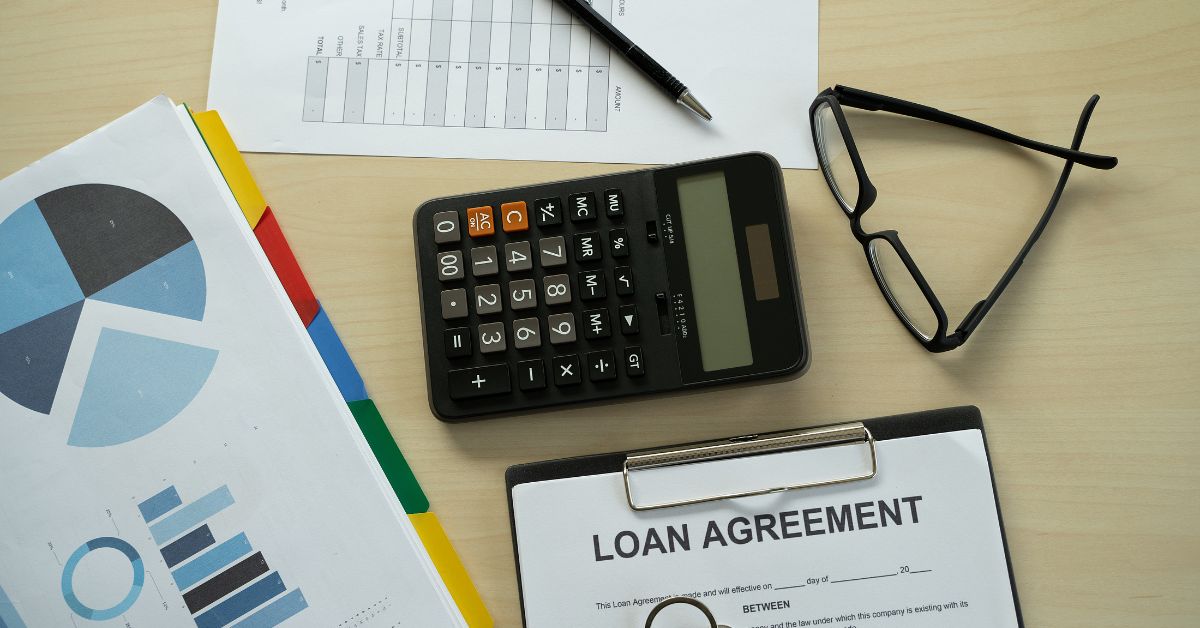 A calculator and loan agreement on a desk with a Title Loans sign above it