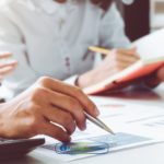 Two people sitting at a table with a calculator and pen learning about consumer credit definition