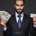 a person holding a dollar bill & credit card in their hand