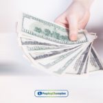 a person holding a dollar bill & phone in their hand