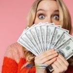 A woman holding a bunch of money from installment loans in front of her face in Arkansas