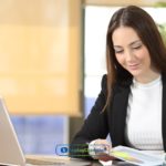 A woman sitting at a desk working on a laptop while reading about mutual credit