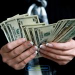 a person holding a dollar bill in their hand.