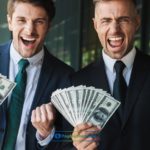 two person holding a dollar bill in their hand.