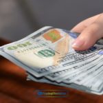 a person holding a dollar bill in their hand.