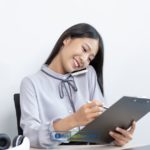 A woman sitting at a desk with a clipboard calling a lender to get a loan with no income verification