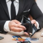 A man in a suit is holding a wallet looking for ways to increase their credit limit and reap the benefits