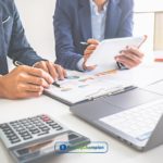 Two people calculating open credit interest rate at a table using a laptop and calculator