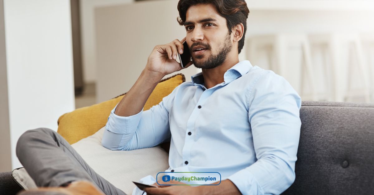 A man sitting on a couch searching for unsecured auto loans using his cell phone