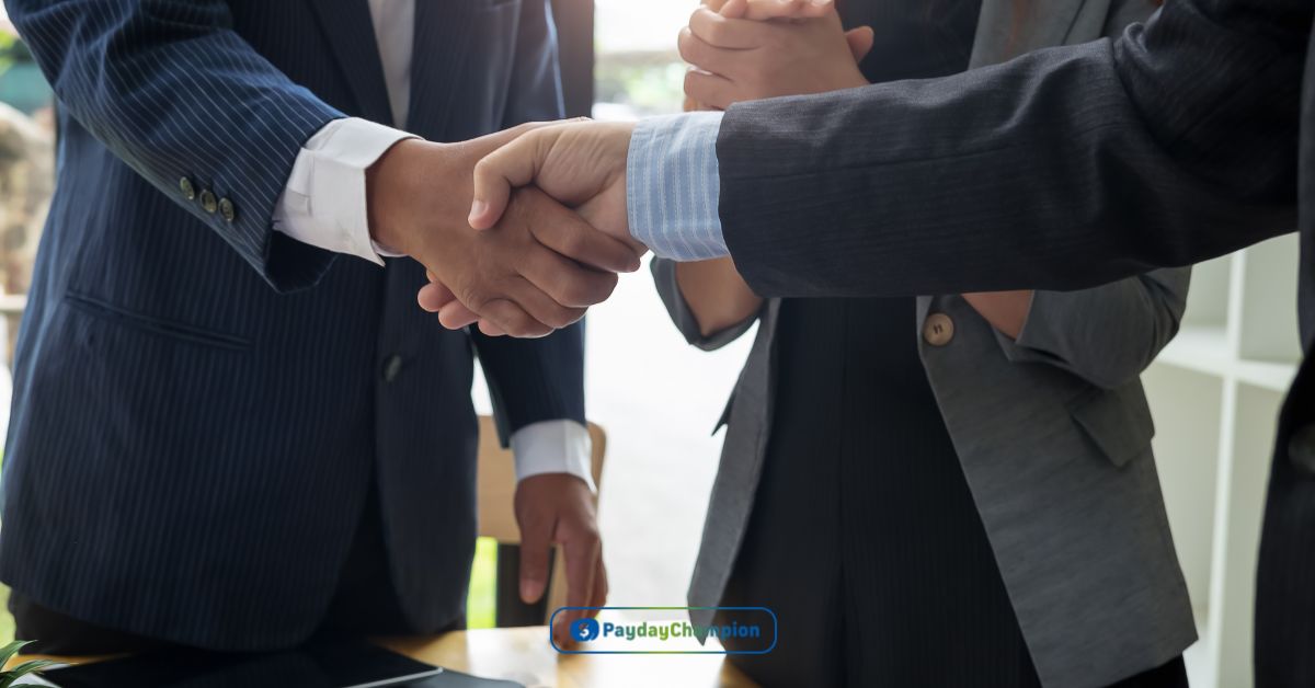 Two men shaking hands in front of a laptop after agreeing on a trade credit plan for their business