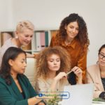 A group of women sitting around a laptop computer discussing payday loans Denver