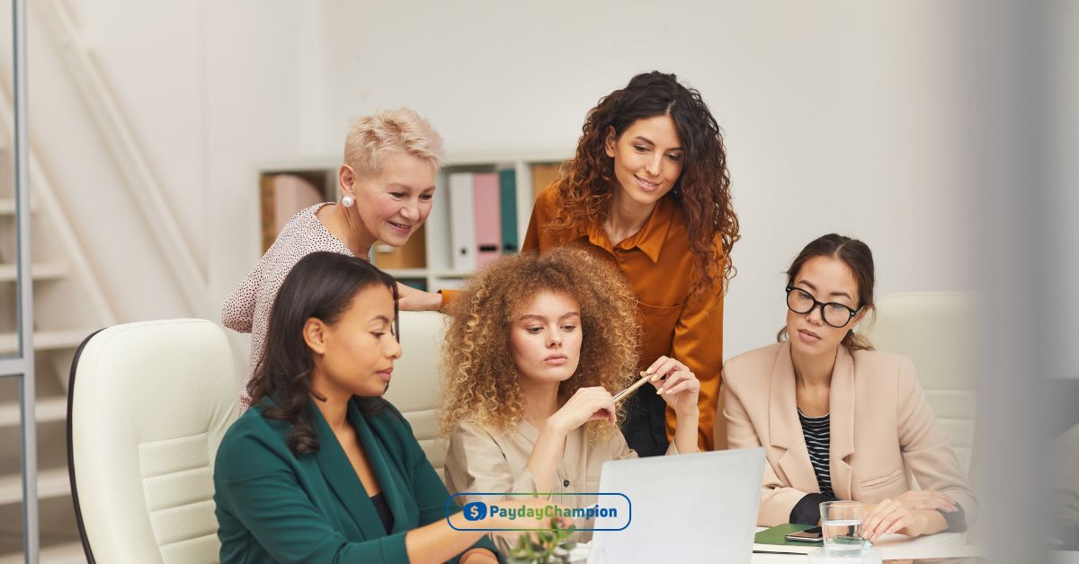 A group of women sitting around a laptop computer discussing payday loans Denver