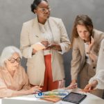 A group of women standing around a table analyzing payday loans Memphis