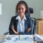 A woman sitting at a desk in her Phoenix payday loans office with her arms crossed