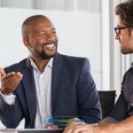 two men sitting at a table talking to each other